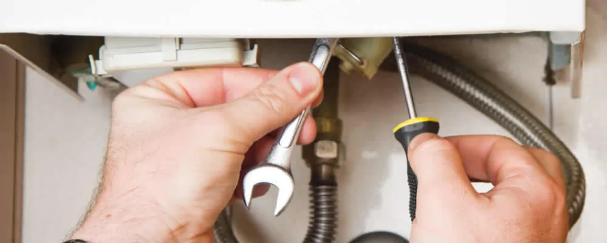 Boiler repair technician tightening pipe fittings and connections in Beverly, MA