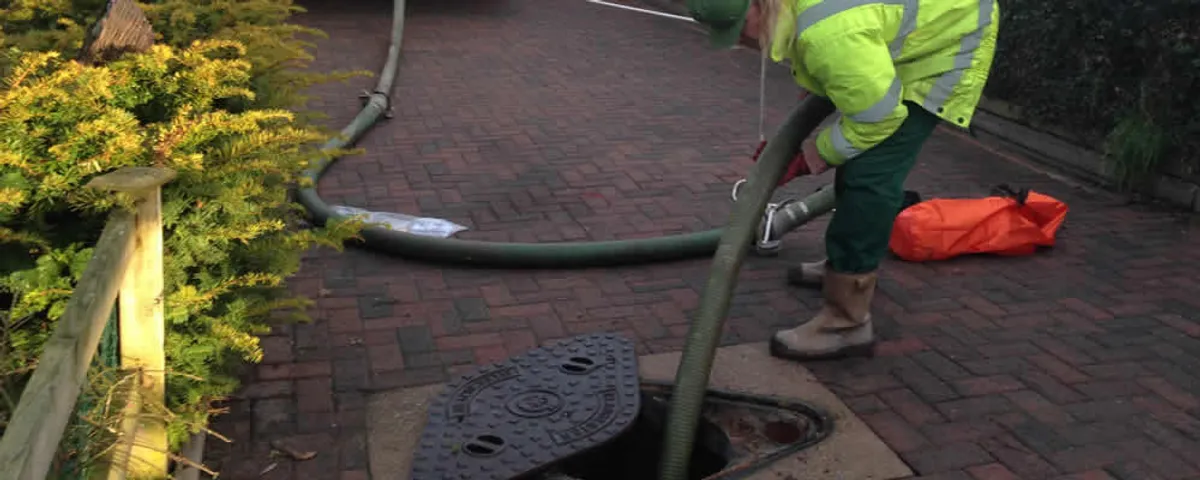 Septic tank cleaning technician servicing a septic tank with a vacuum hose in Beverly, MA