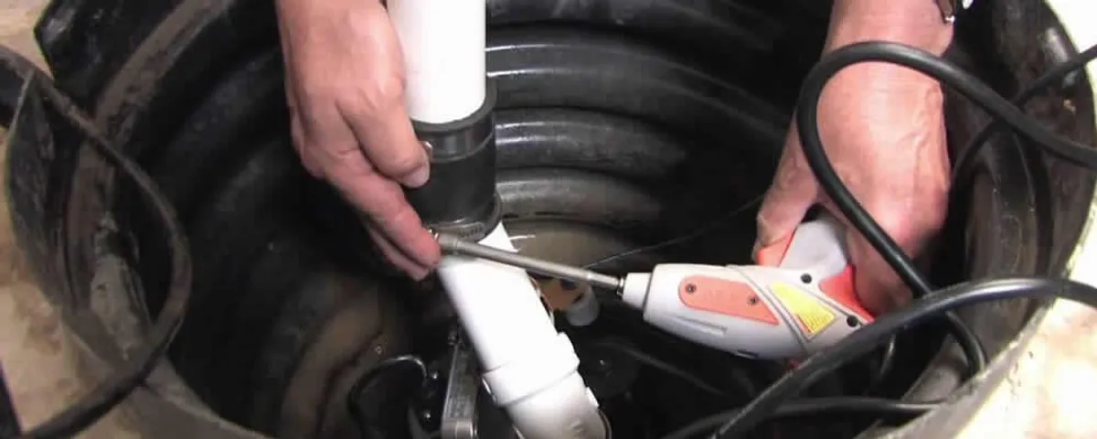 Sump pump installation technician connecting PVC discharge piping in Beverly, MA